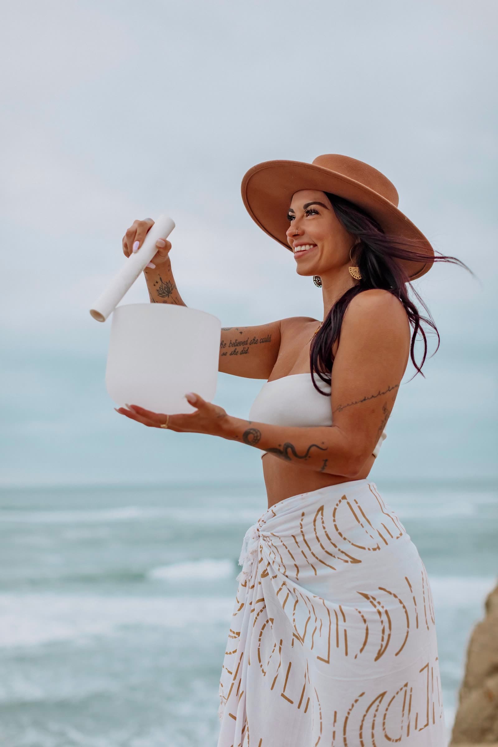 Kaitlyn holding a crystal singing bowl beside the ocean